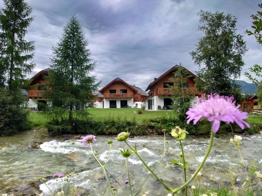 a house with a river and flowers in front of it at AlpiNest Feriendorf Lungau in Mariapfarr