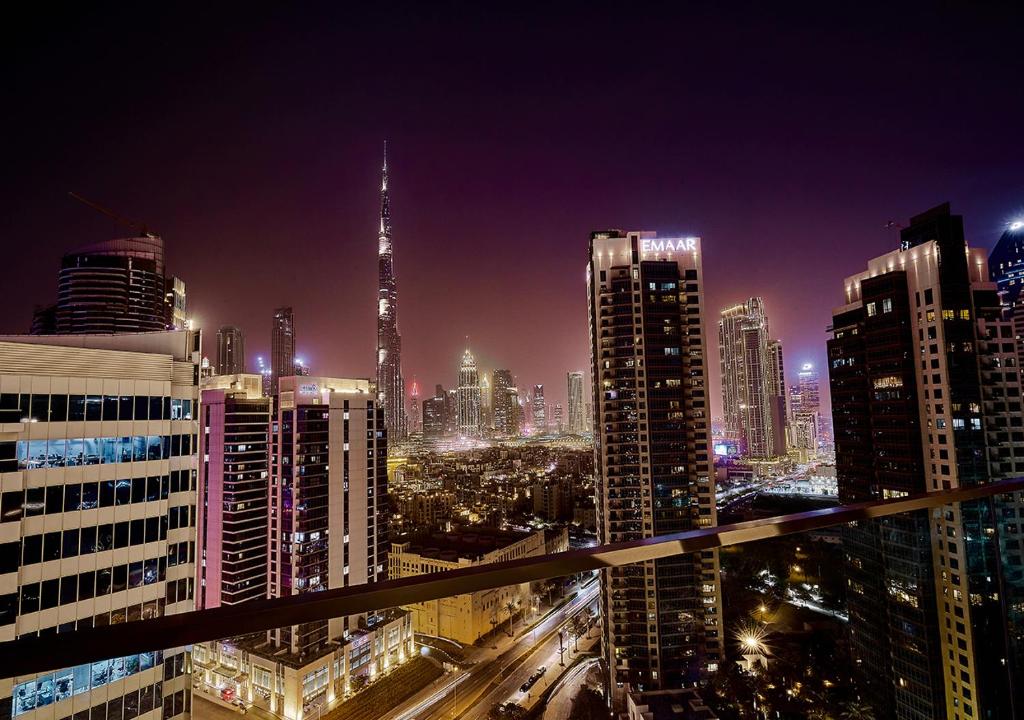 a view of a city at night with buildings at Luxury Studios with Burj Khalifa or Canal View in Downtown - Marquise Square Tower in Dubai