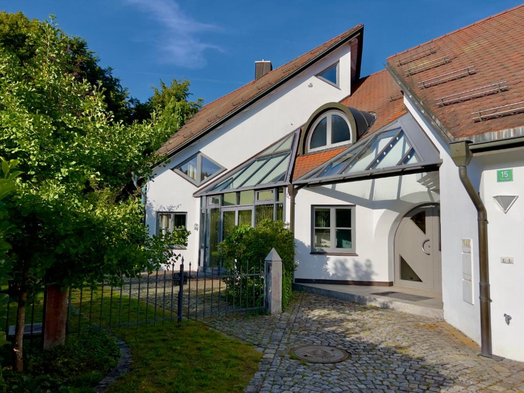 una casa bianca con tetto rosso e cancello di Ferienwohnung BAYERNRING a Breitenbrunn