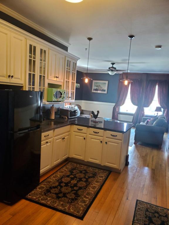 a kitchen with white cabinets and a black refrigerator at Firehouse Inn in Barre