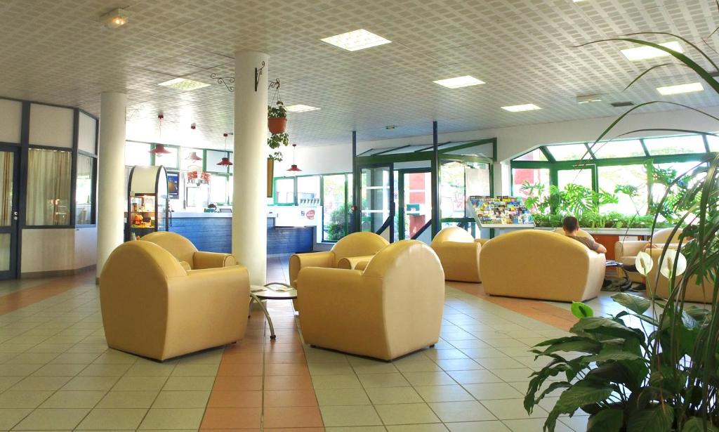 a lobby with yellow chairs and people in a store at VVF Urrugne Saint-Jean-de-Luz Côte Basque in Urrugne
