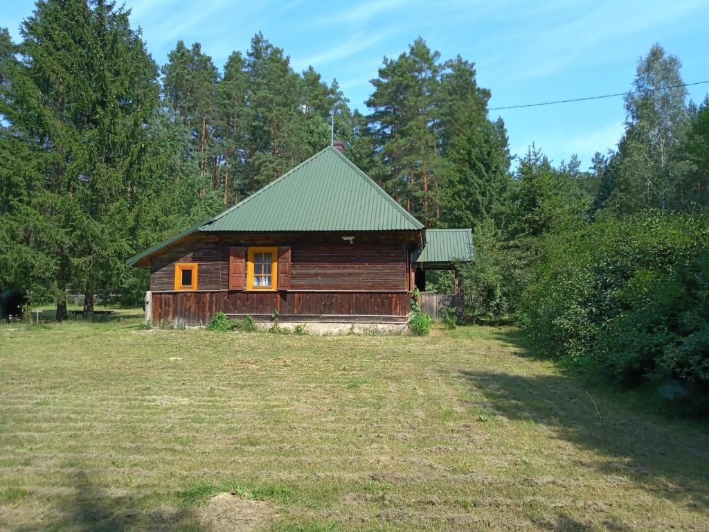 a small wooden cabin in a field with trees at Leśniczówka Turowo - Podlasie 