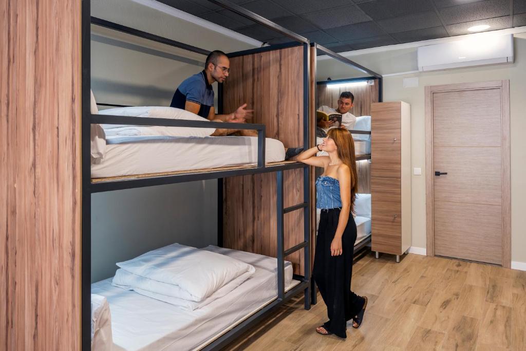 a woman standing in front of two bunk beds at SOM Hostel By The Venue in Valencia