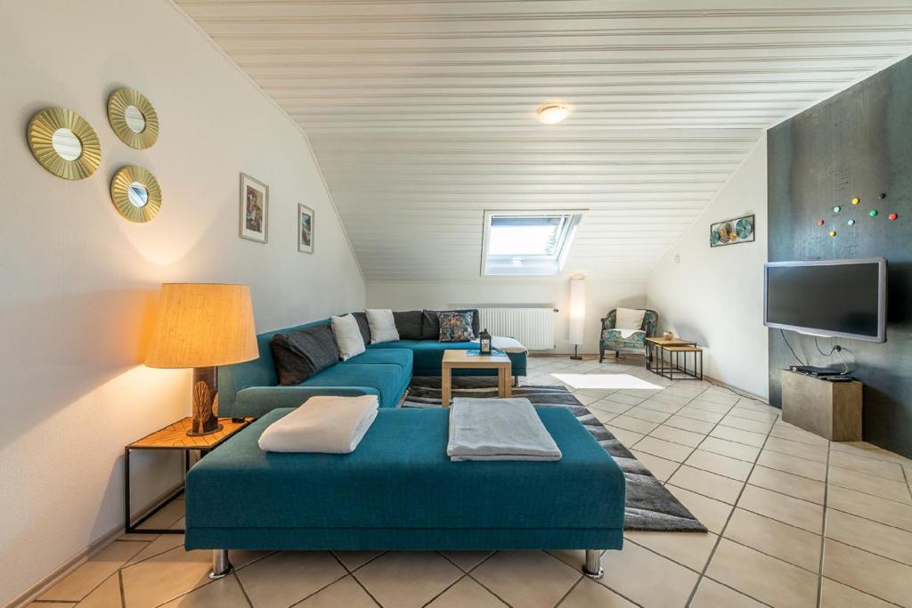 sala de estar con 2 sofás azules y TV en Ferienwohnung Am Steinchen, en Mettlach