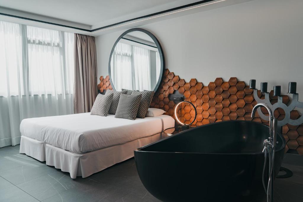 a bedroom with a bed and a tub and a mirror at Poem Suites, Las Canteras in Las Palmas de Gran Canaria