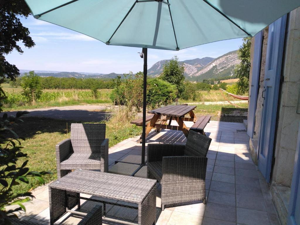 a patio with a table and chairs and an umbrella at Gîte Clé des Champs in Saint-Laurent-en-Royans