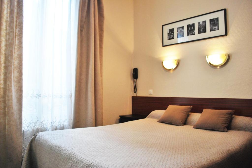 a bedroom with a bed with two pillows and a window at Hôtel Avenir Jonquière in Paris