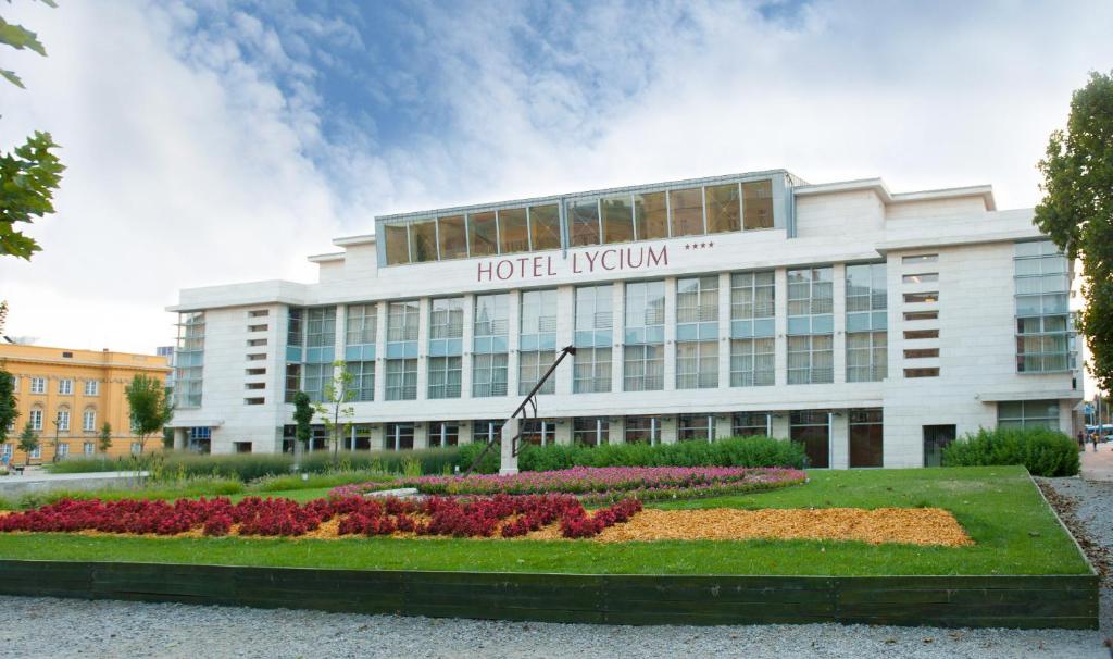 un hotel edificio kyiv con flores delante en Hotel Lycium Debrecen, en Debrecen