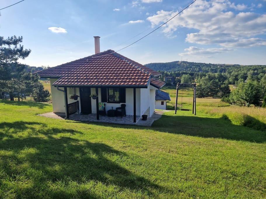 ein kleines Haus auf einem Feld mit einem Rasenplatz in der Unterkunft Povetarac in Divčibare