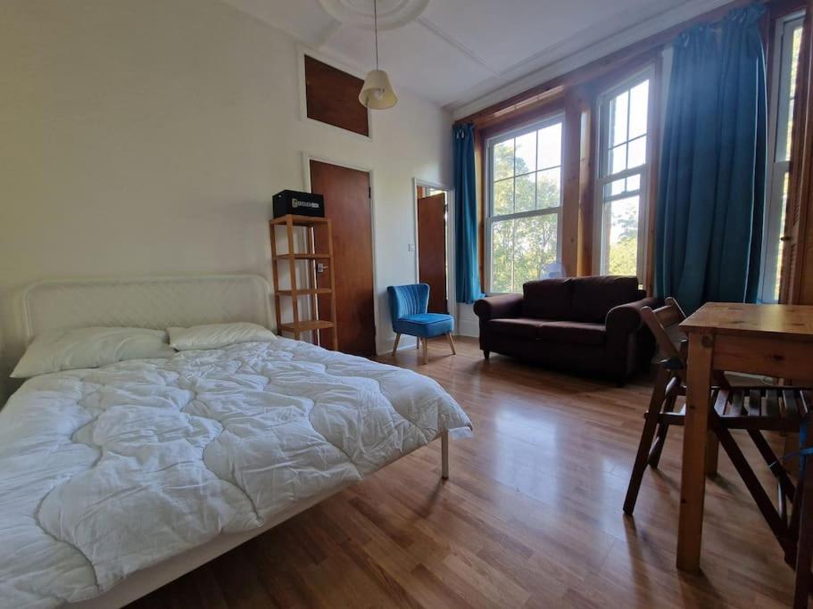 een slaapkamer met een bed, een bureau en een tafel bij Bright well located studio flat in Londen