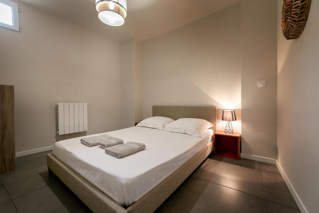 1 dormitorio con 1 cama blanca y 2 toallas en Perpignan - Appartement en centre ville, en Perpiñán