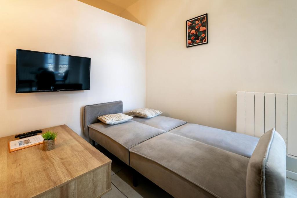 a bedroom with a bed and a table and a flat screen tv at Perpignan - Appartement en centre ville in Perpignan