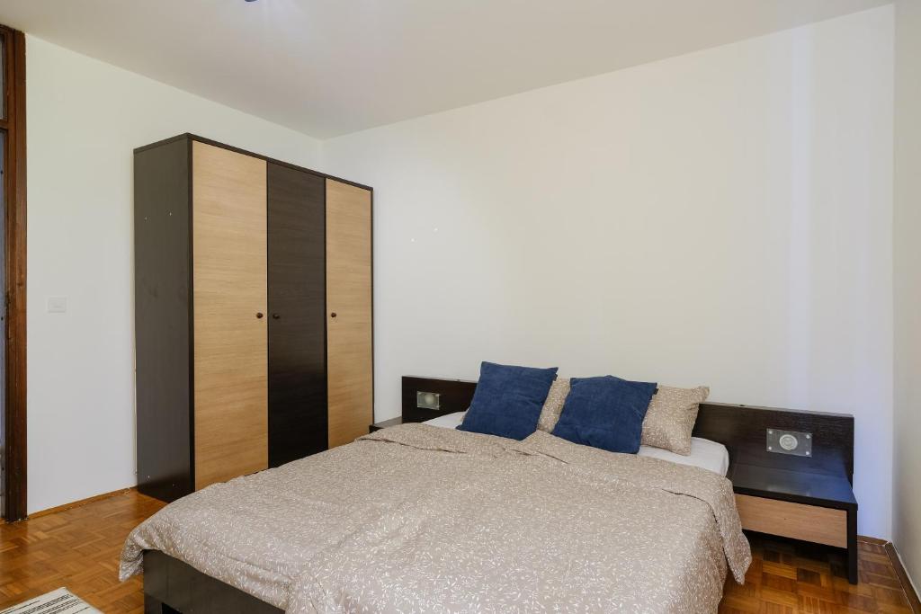 a bedroom with a large bed with blue pillows at BLOK apartment in Visoko