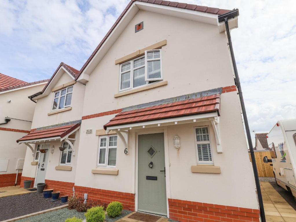 a white house with a green door and red bricks at 6 Cwrt Griffiths in Rhyl