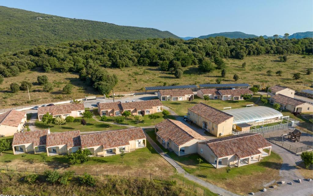 una vista aerea di un'azienda agricola con un gruppo di case di Park & Suites Village Gorges de l'Hérault-Cévennes a Brissac
