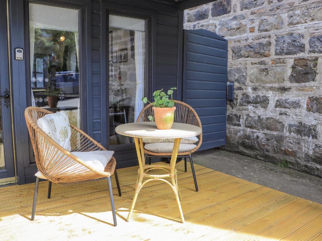 a table and chairs on a porch with a potted plant at Creed Cabin in Stornoway