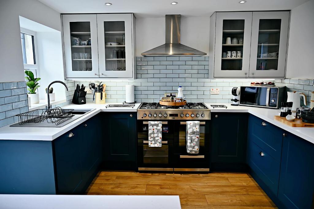 een keuken met blauwe kasten en een fornuis met oven bij Porthmadog, Sleeps 11, 5 Bedrooms, 5 Bathrooms, Mountain Views in Porthmadog
