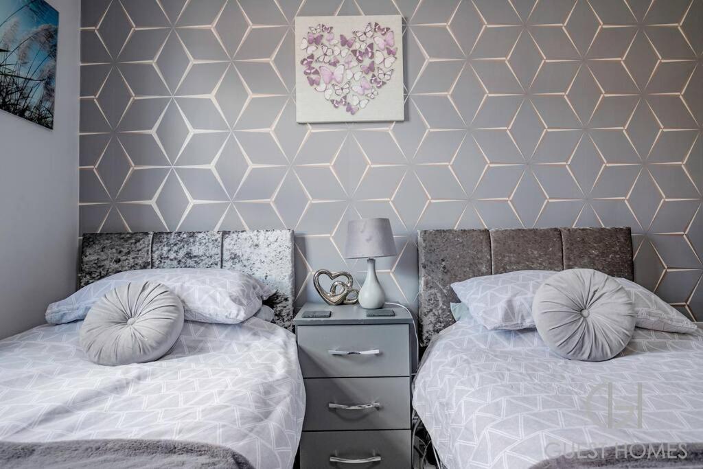 a bedroom with two beds and a geometric wall at Guest Homes - Calthwaite House in Brough