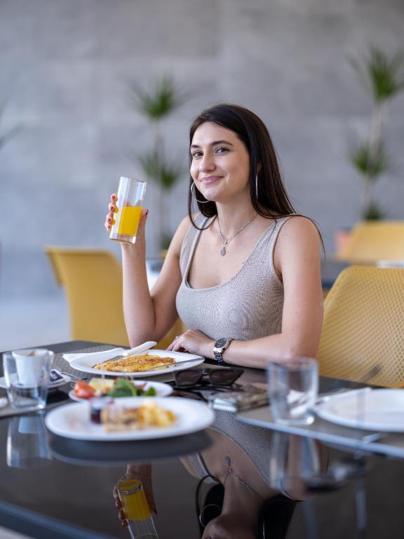 Una donna seduta a un tavolo con un bicchiere di birra di Hotel D'Elegant Dubrovnik a Dubrovnik