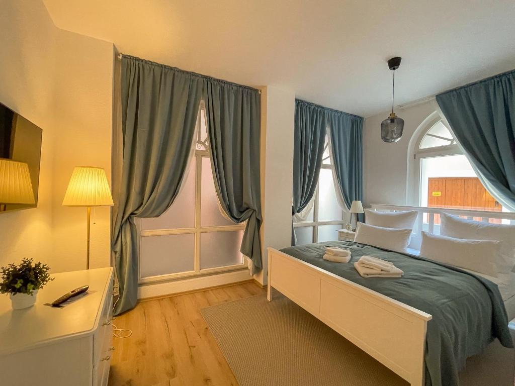 a bedroom with a bed with blue curtains and a window at ApartOne Altstadt-Apartments in Bautzen