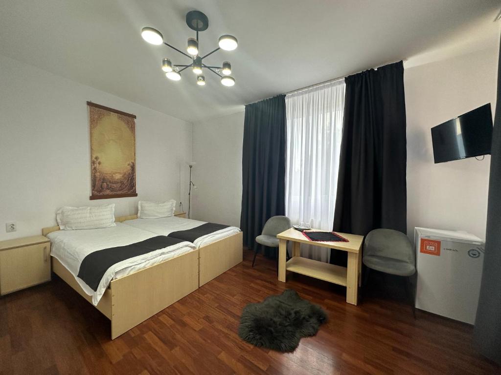 een slaapkamer met een bed, een tafel en een raam bij Pensiunea Brici in Cluj-Napoca