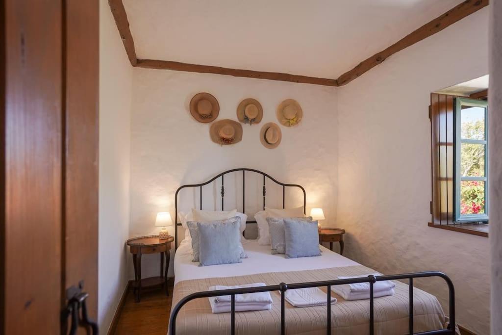 a bedroom with a bed with white sheets and pillows at Charming Cottage in Almoçageme in Colares