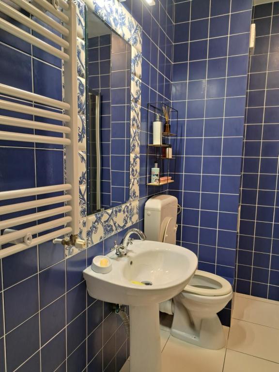 La salle de bains est pourvue de carrelage bleu, de toilettes et d'un lavabo. dans l'établissement apartament Onestilor, à Oradea