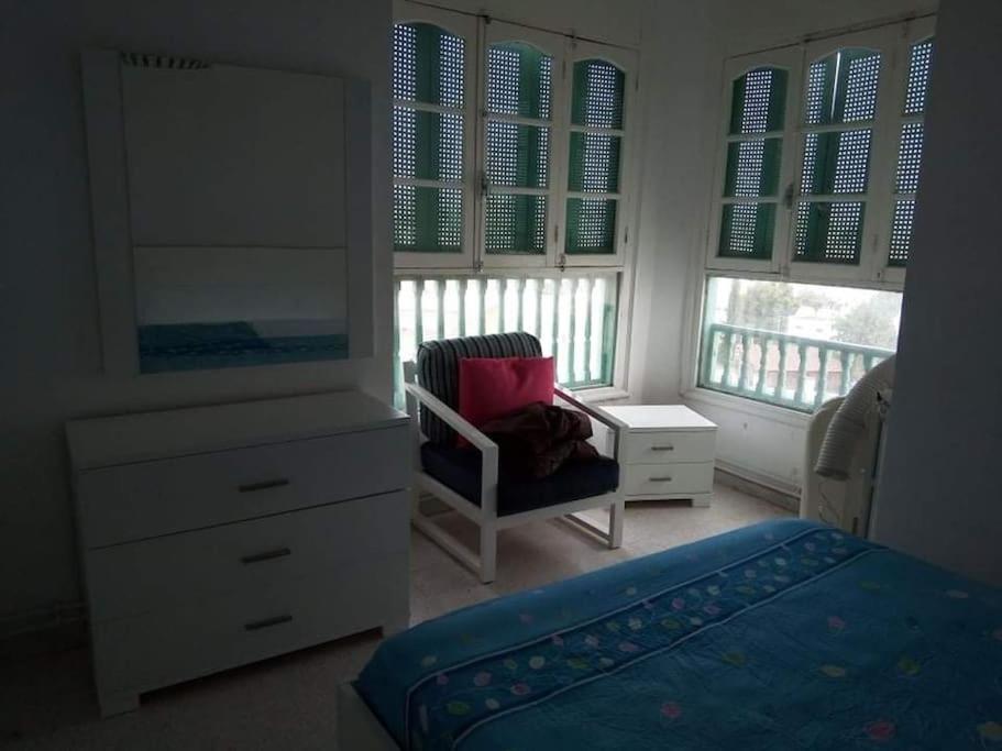 a bedroom with a dresser and a bed and a chair at Tunis Comfort Family Home in Burj at Turkī