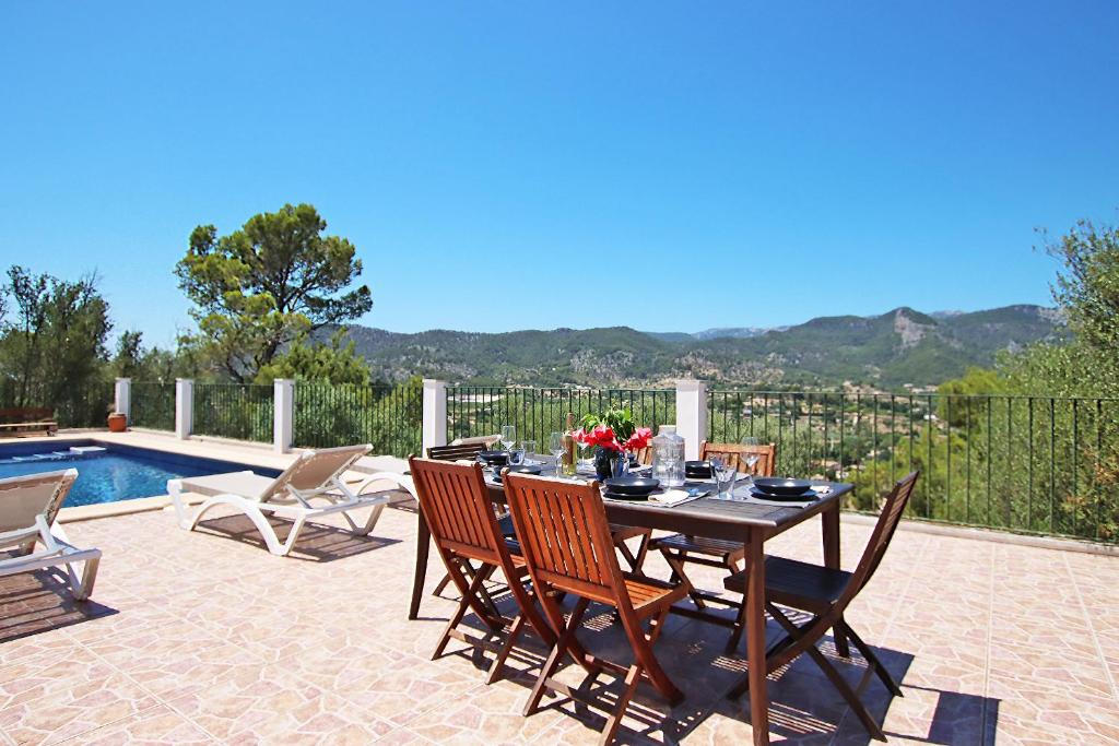 un tavolo da pranzo e sedie su un patio accanto alla piscina di Villa Ses Costes by Slow Villas ad Alaró
