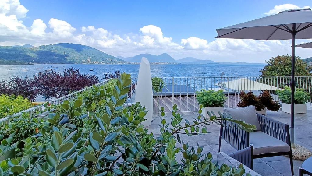 a patio with chairs and an umbrella and a view of the water at La Romantica in Feriolo