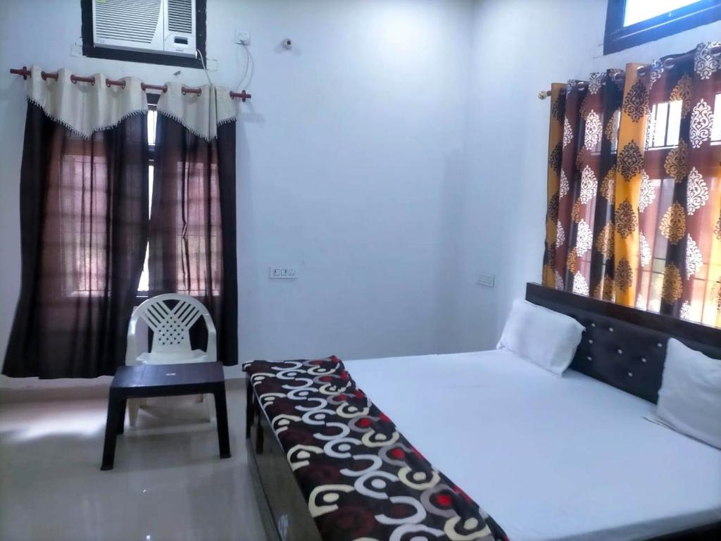 a bedroom with a bed and a chair and a window at HOTEL SAMRAT PALACE in Ayodhya