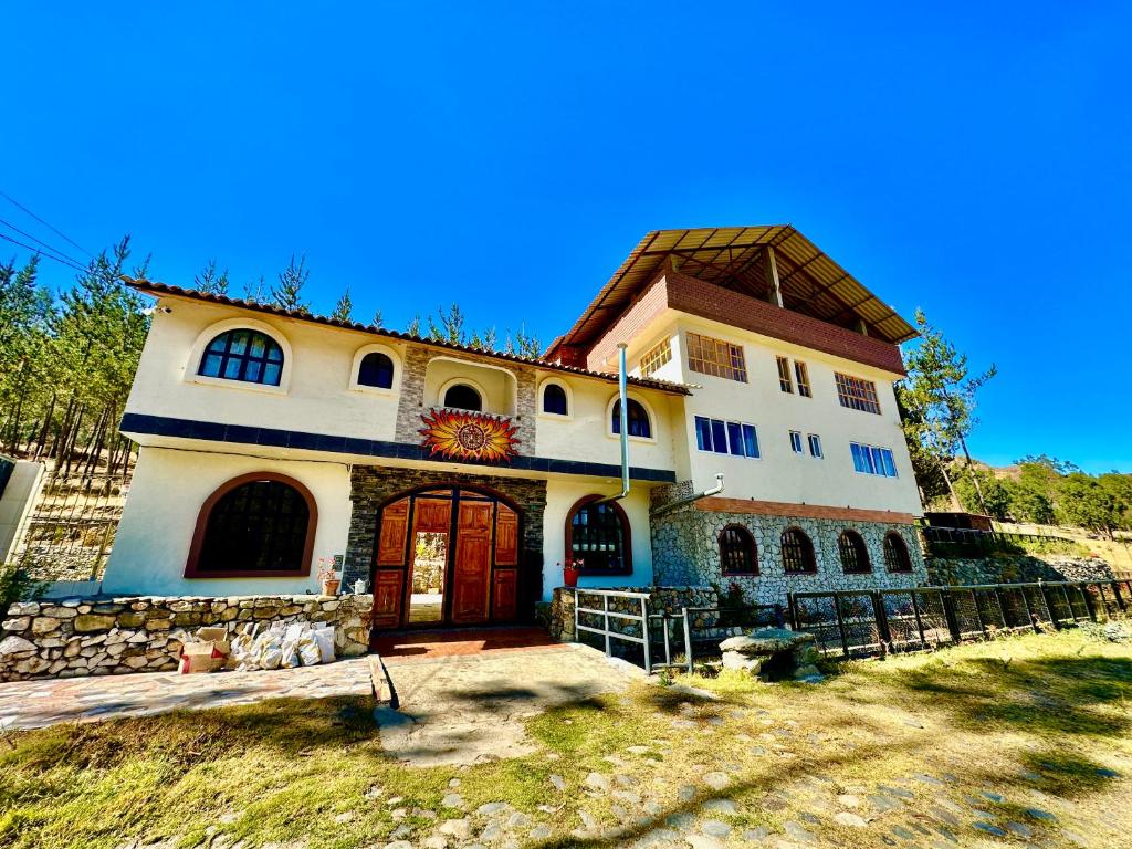 une grande maison blanche avec un toit marron dans l'établissement Chacraraju Lodge, à Huaraz
