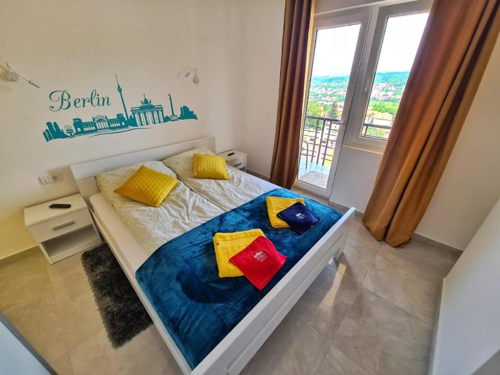 Un dormitorio con una cama con almohadas de colores y una ventana en Apartman Berlin Sokobanja en Soko Banja