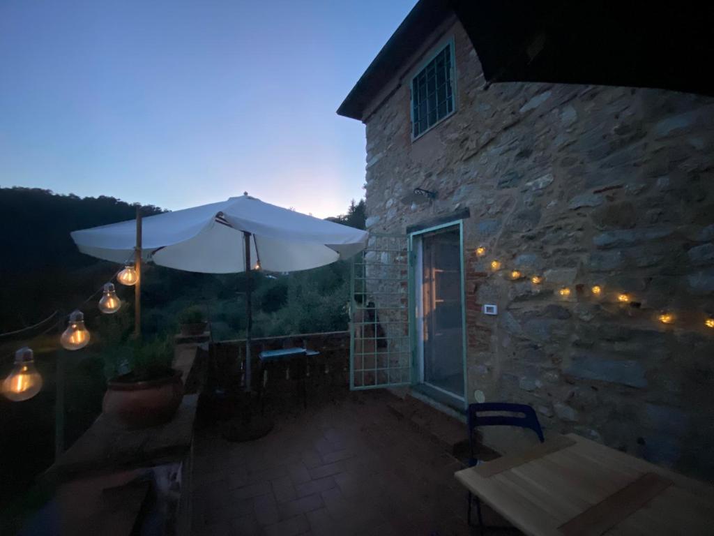 a patio with an umbrella and a table and chairs at Casa spaziosa in caratteristico paesino di alta collina in Santa Maria Albiano