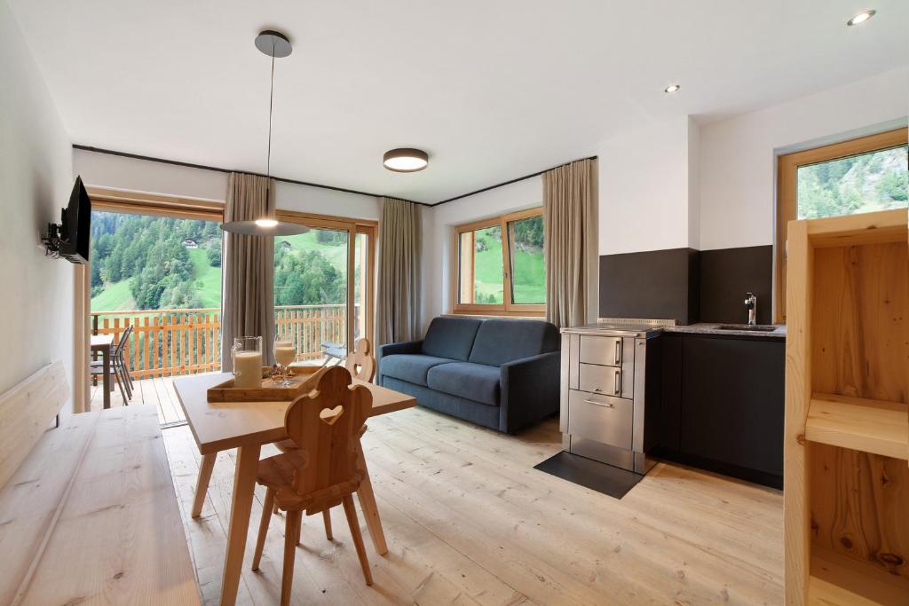 a kitchen and living room with a table and a couch at Herrischner Apartement 1 in Corvara in Passiria