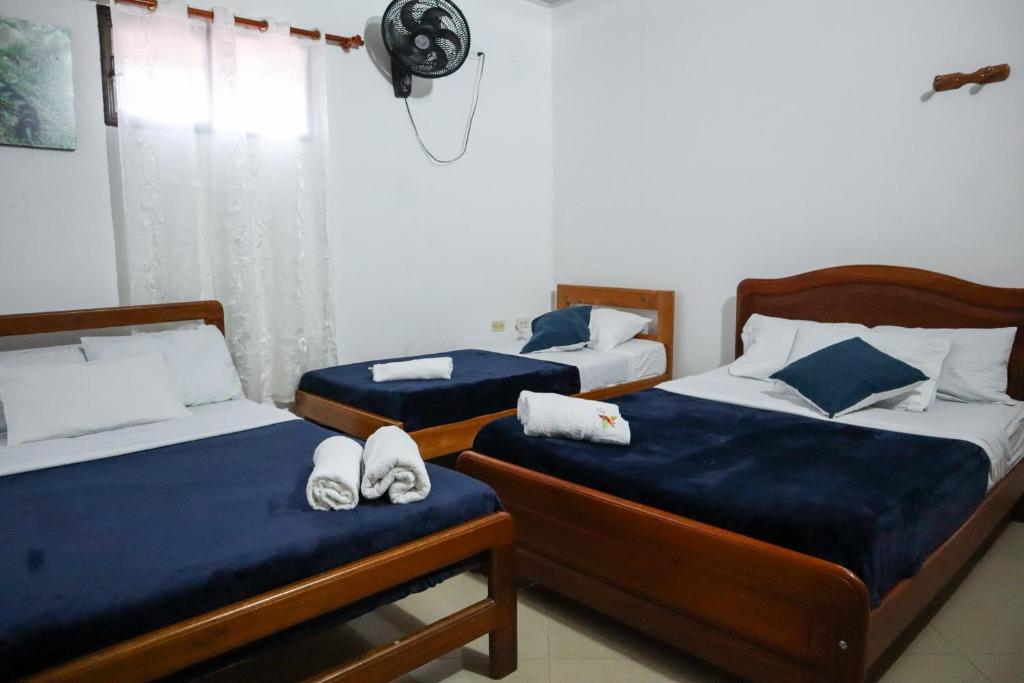 1 dormitorio con 2 camas con sábanas azules y ventilador en Hotel Los Almendros en Santa María