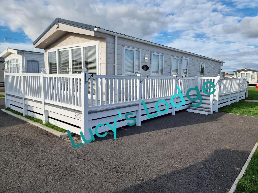 a mobile home with a white fence at Lucy's Lodge in Rhyl