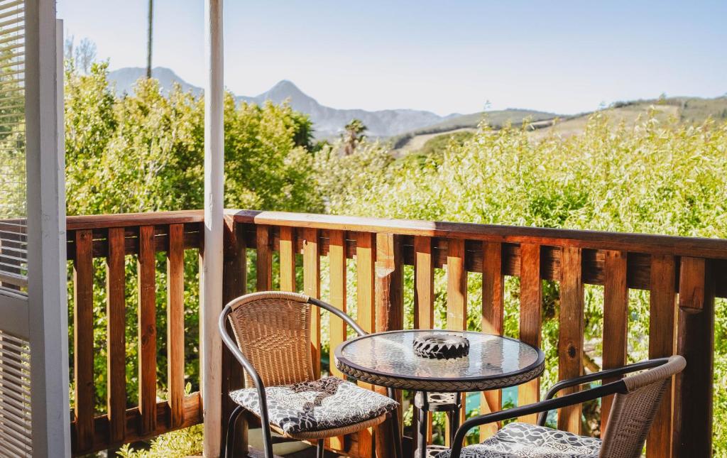 a table and chairs on a balcony with a view of mountains at Brookwood Cottage in Somerset West