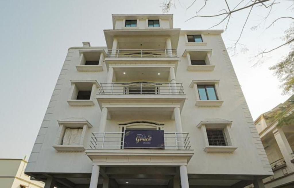 een hoog wit gebouw met een paars bord erop bij Goroomgo Grace Premium Bhubaneswar in Bhubaneshwar