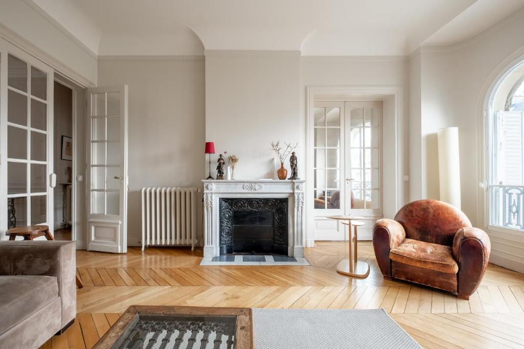 ein Wohnzimmer mit einem Kamin und einem Stuhl in der Unterkunft Veeve - A Window to Paris in Paris