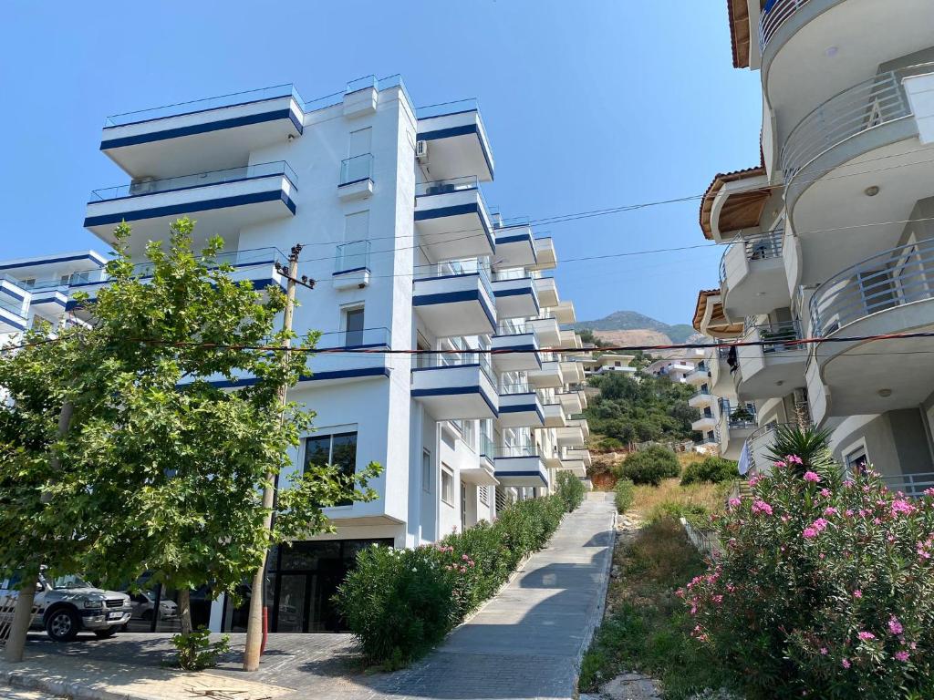 ein weißes Apartmenthaus mit Balkonen und Bäumen in der Unterkunft LIV Apartments in Vlorë