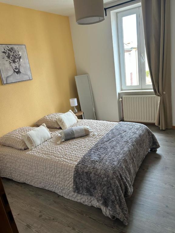Hotel Le petit coin des oliviers, a bedroom with a bed with two pillows and a window at Le petit coin des oliviers in Colmar