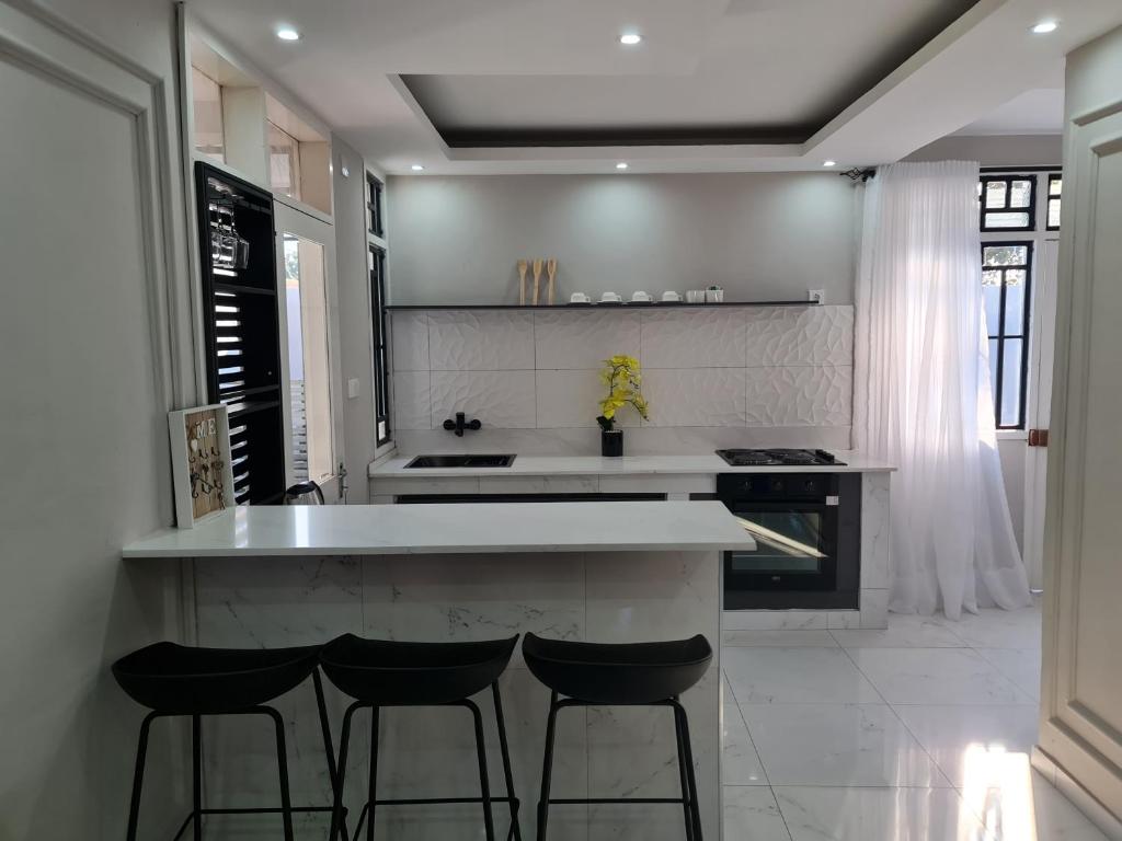 a kitchen with a white counter and stools in it at Pousada Calma in Maputo