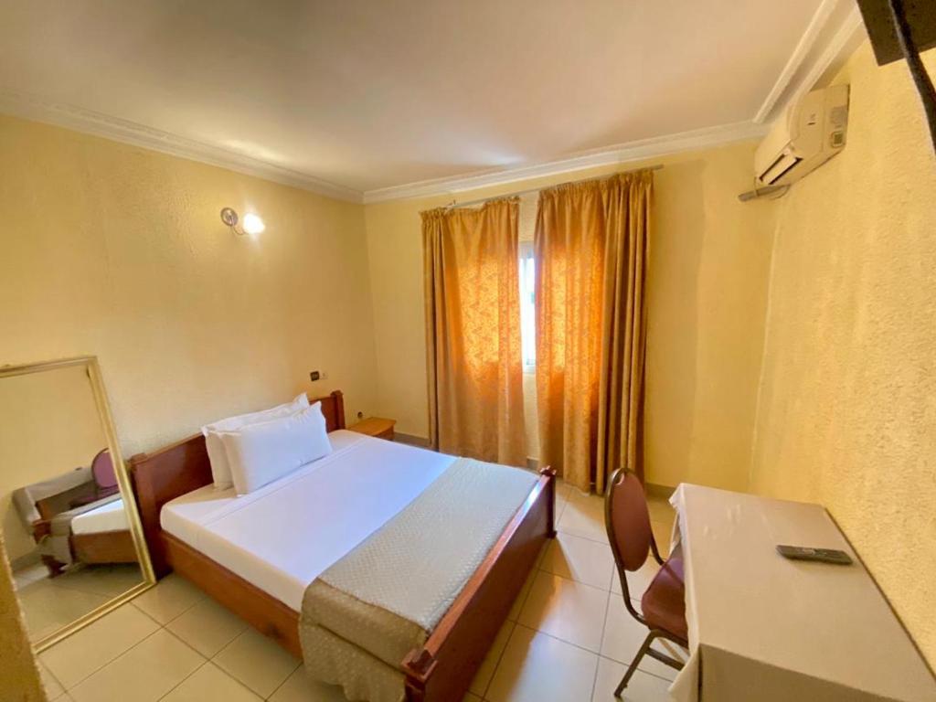 a bedroom with a bed and a table and a window at First International Inn Downtown in Limbe