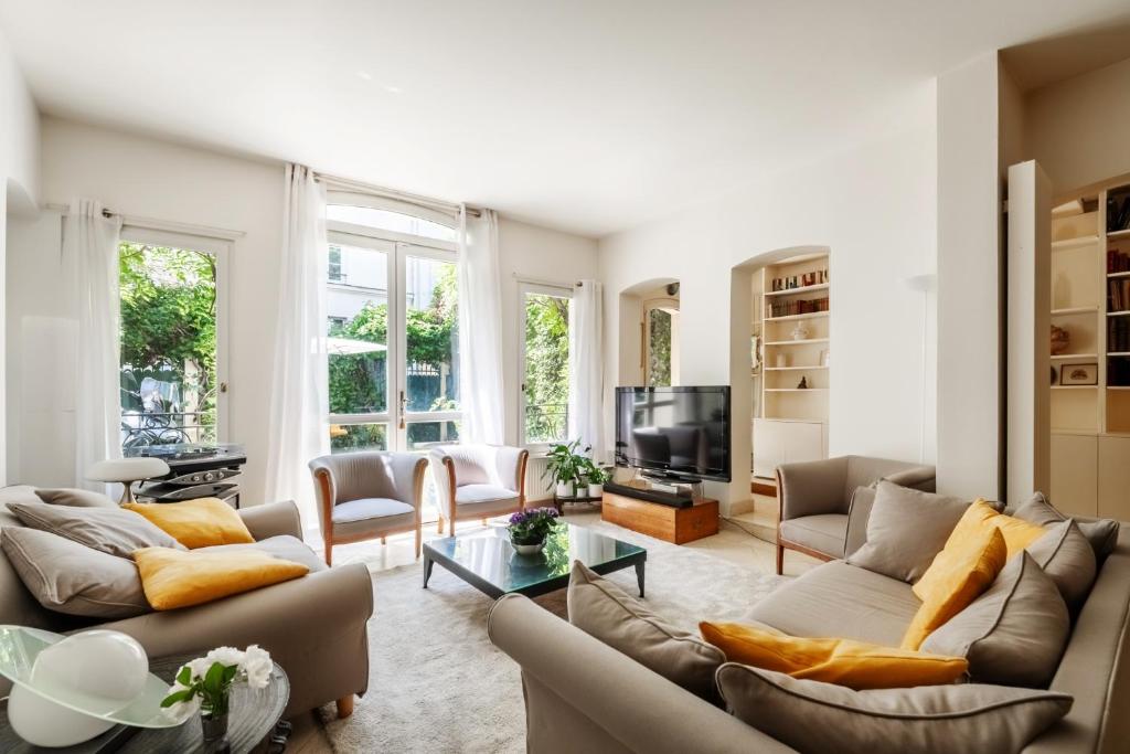 un salon avec deux canapés et une télévision dans l'établissement Veeve - Gilded Garden Splendour, à Paris