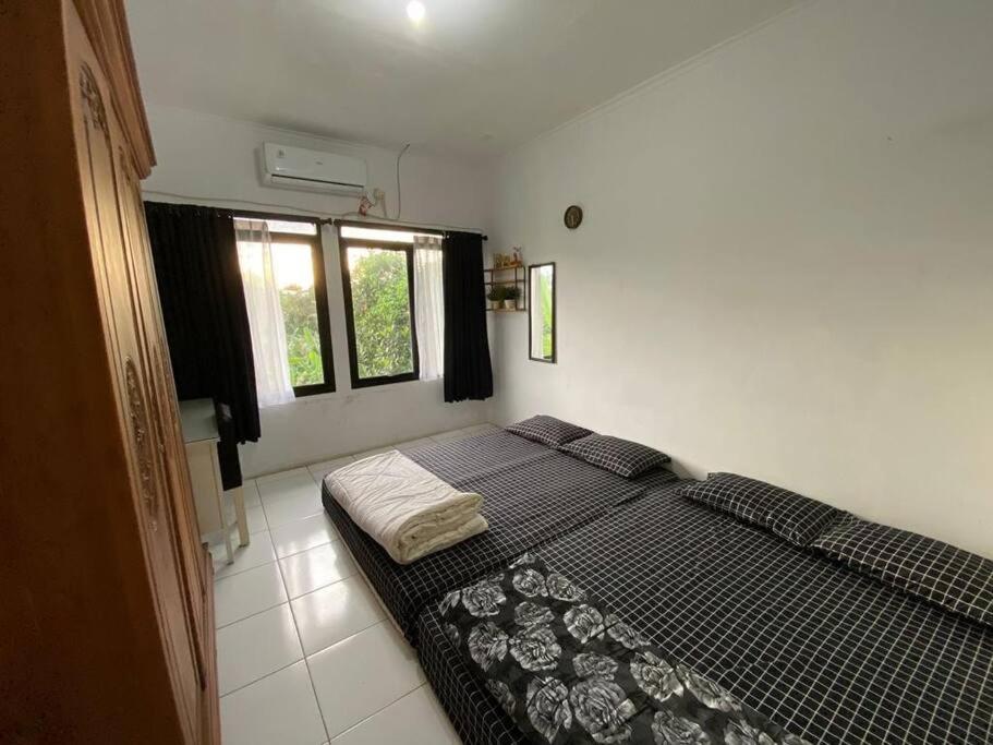 a bedroom with a bed and two windows at Coral House - Near Univ Indonesia Setu Babakan in Jakarta