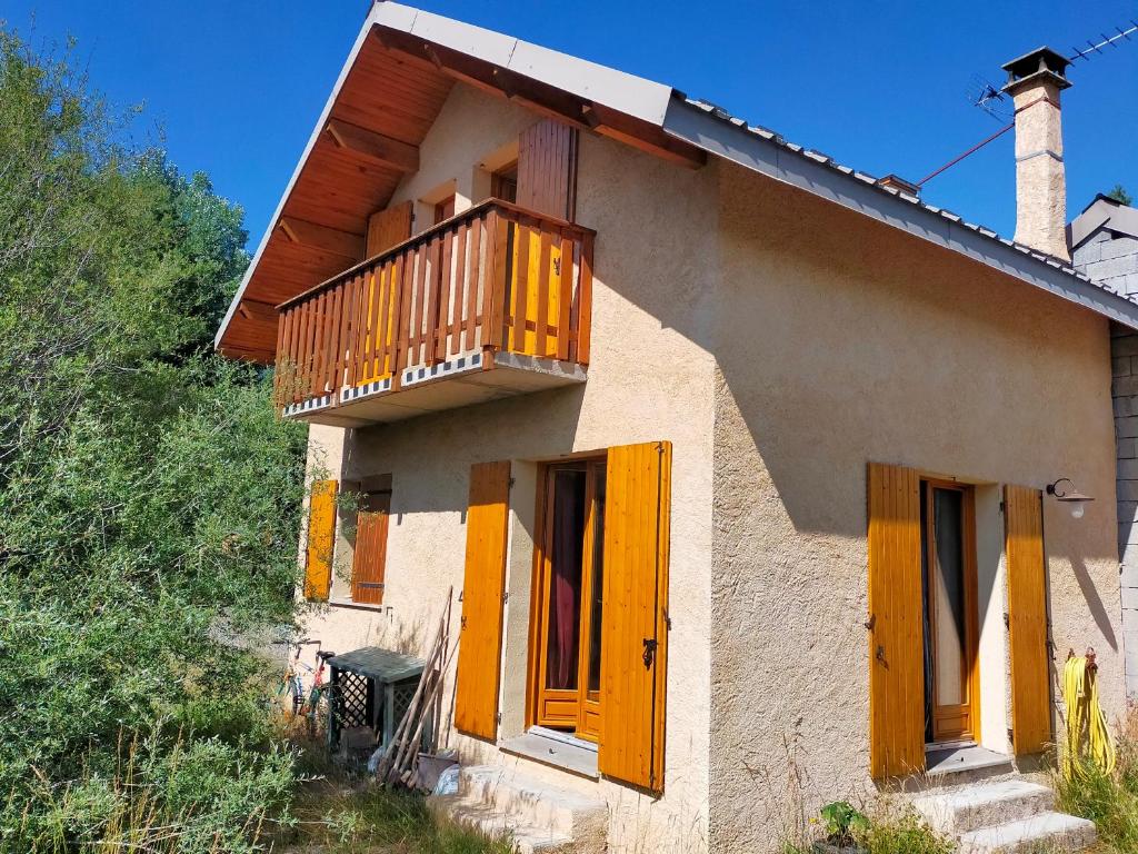 a house with yellow doors and a balcony at Maison lotissement du Bérard in Faucon-de-Barcelonnette