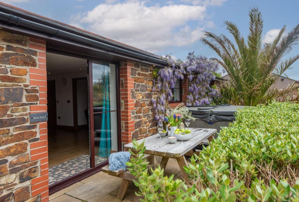 a brick house with a wooden table in the garden at Main Beach in Redruth