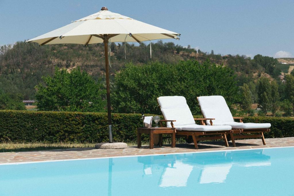 two chairs and an umbrella next to a swimming pool at Casa villetta "La Colomba" Nizza Monferrato in Nizza Monferrato