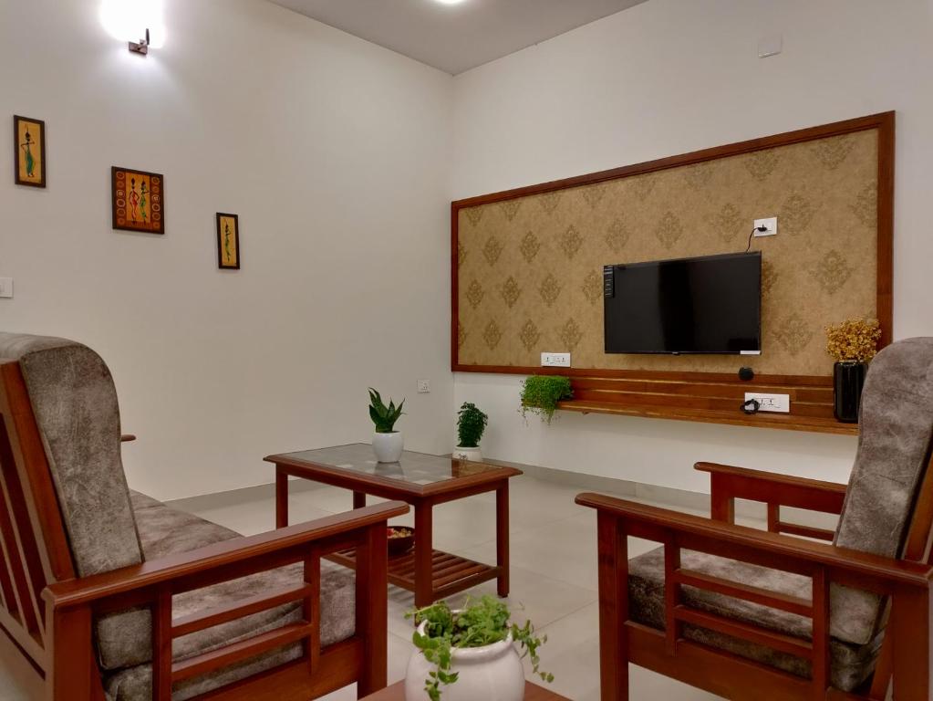 a living room with two chairs and a flat screen tv at The Cana's Coorg in Ammatti